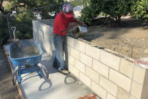 Retaining wall construction. Masonry block cells being filled with concrete to provide additional wall strength
