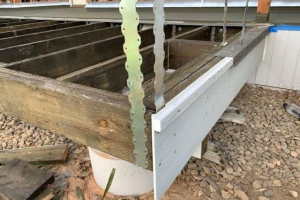 Metal post straps attaching railing posts to subfloor, subfloor fascia and metal floor edge flashing being installed