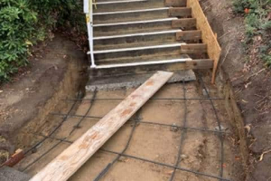 Damaged concrete walkway removed adjacent to stairs, re-bar installed